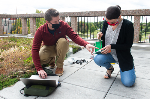 SIUE graduate student Josh Gifford (left) and the STEM Center’s Carol Colaninno, PhD, retrieve data and change batteries in the sensors installed on the Science West Green Roof.